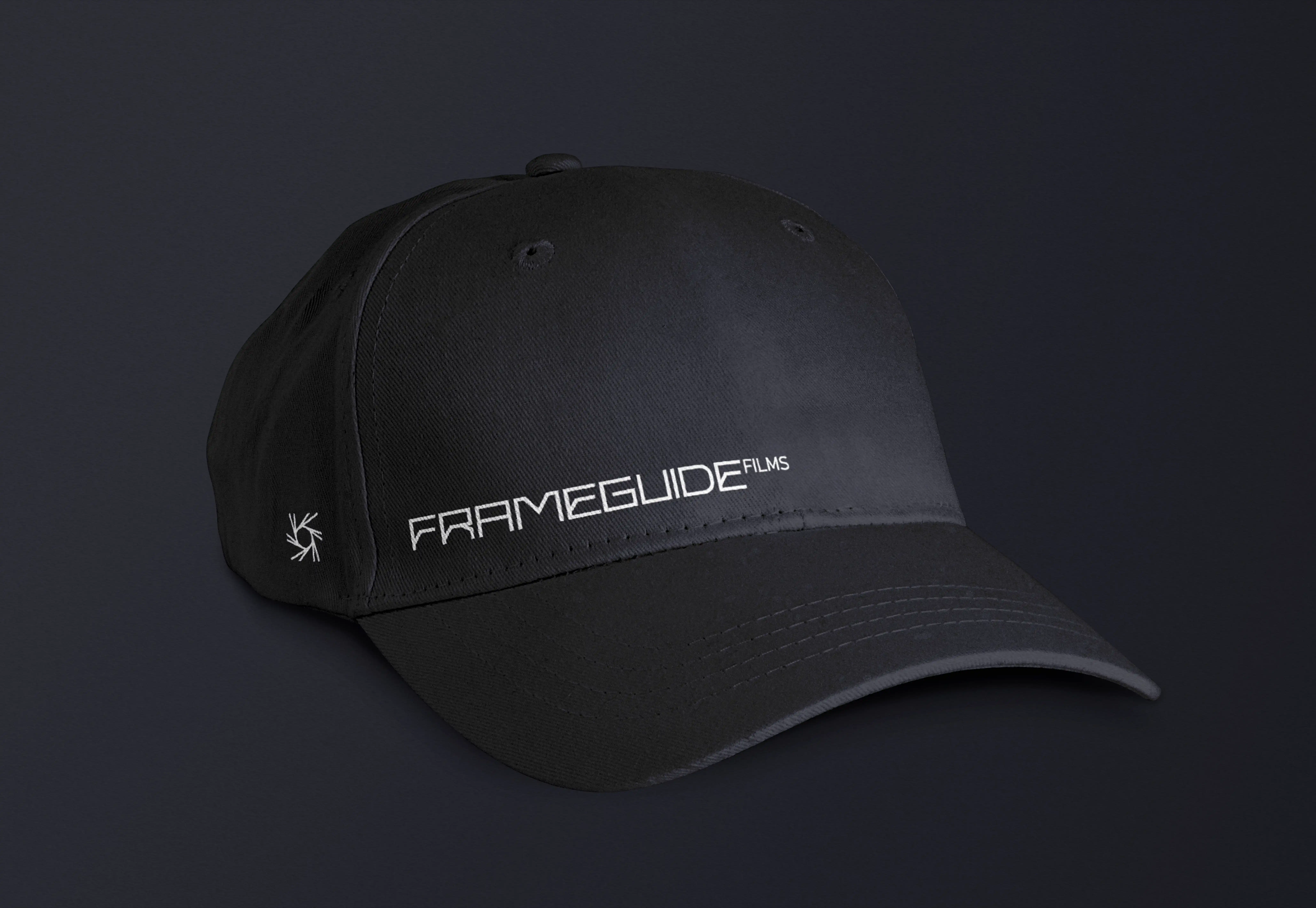 IA-Studio – Branding, Logo Design & Webdesign in Wien Schwarze Baseballkappe mit dem weißen FRAMEGUIDE FILMS Logo, präsentiert auf dunklem Hintergrund als Teil des Markenauftritts eines Videografen.